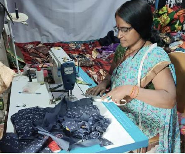 A founder behind the counter of her fabric shop, stock shelved behind her