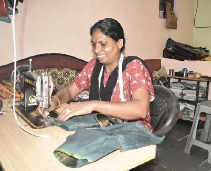 A founder sewing at a machine in her home workshop